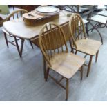 An Ercol elm drop leaf dining table, the oval top raised on square,
