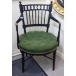 An ebonised open arm chair, in the style of EW Godwin, having a round back with a carved, conjoined,