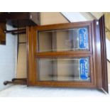 An early 20thC oak display cabinet with a straight cornice, over a pair of glazed, panelled doors,