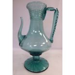 A tinted green glass pedestal ewer of bulbous form with a ribbed neck,