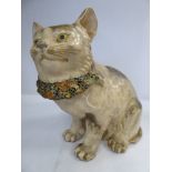 A late 19thC Japanese Satsuma earthenware model, a seated cat with an enamelled and ribbon collar,