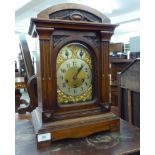 An early 20thC carved walnut cased mantel clock with an arched top and straight sides,