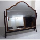 A 1930s dressing table mirror, the arched, bevelled plate set in a cushion moulded mahogany frame,