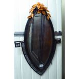 A lozenge shaped bevelled mirror, set in a patinated iron, faux wood frame with Greek key motifs,