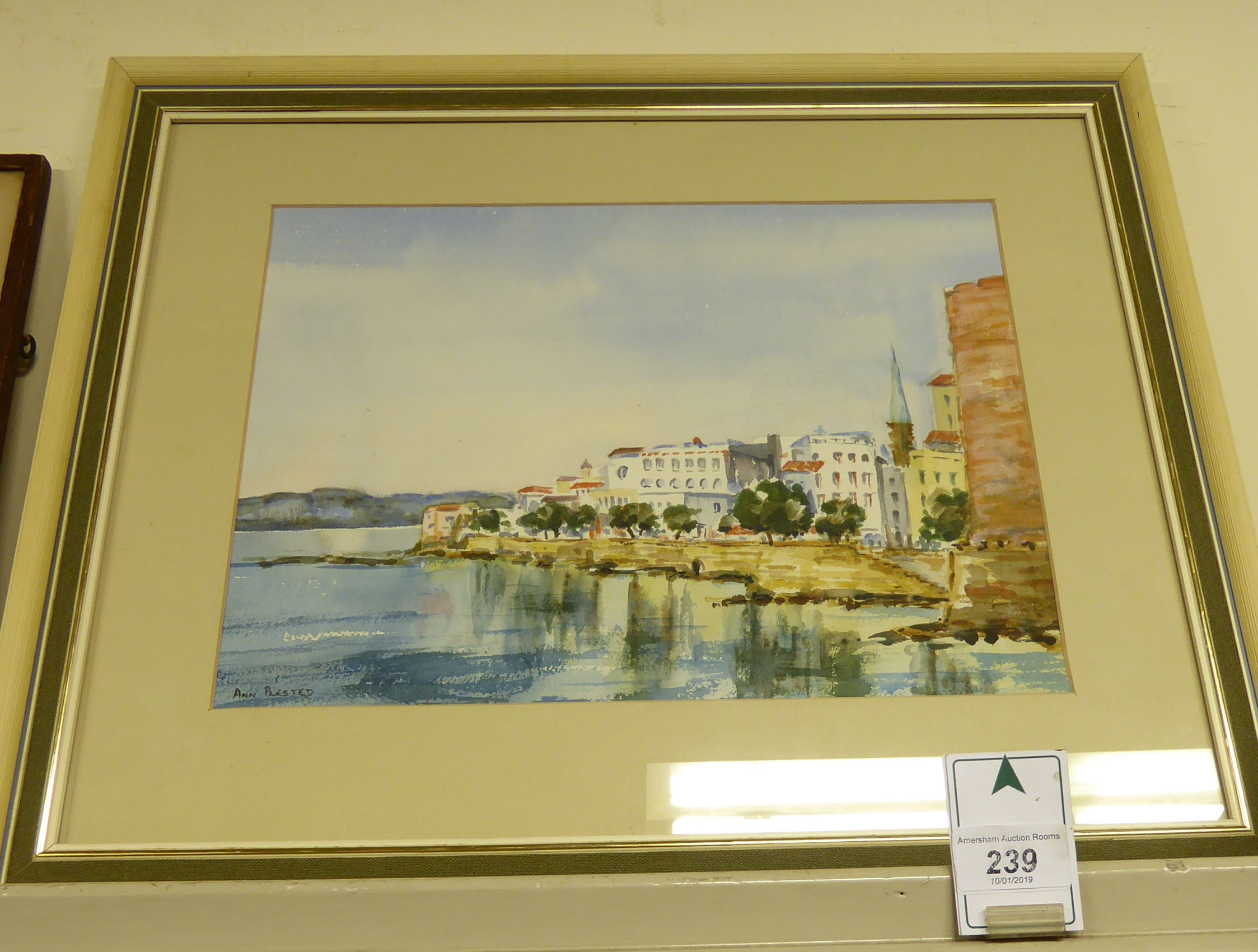 Ann Plested - a Mediterranean shoreline scene with a small town beyond watercolour bears a