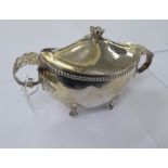 A silver coloured metal navette shaped sauce tureen with a cover and floral knop,