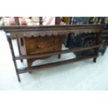 A George III stained oak dresser plate rack with a moulded cornice, shaped frieze and two shelves,