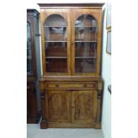 A mid Victorian satin mahogany cabinet bookcase, the upper part comprising a pair of arched,