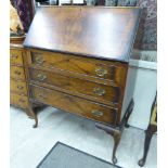 A 1930s crossbanded walnut bureau with a fall flap, enclosing a fitted interior,