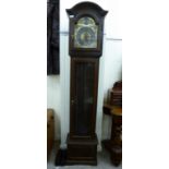 A 20thC stained oak longcase clock, the hood with an arched window, over a glazed pendulum door,