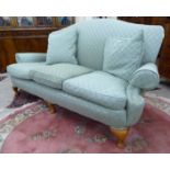 A mid 20thC Queen Anne inspired three person cottage settee with an arched back and scrolled arms,