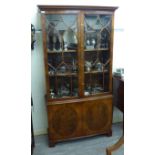 A modern yewwood cabinet bookcase with a pair of glazed doors, over two doors,