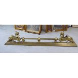 An early 20thC brass fire curb with two opposing winged beasts,