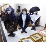 Three modern dissimilar painted porcelain dolls' heads wearing fabric clothes,