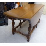 An Ercol elm drop leaf coffee table, the oval top raised on bobbin turned legs,