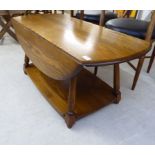 An Ercol elm drop leaf coffee table, the oval top raised on turned legs,