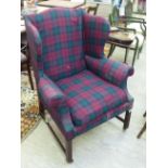 An Edwardian tartan fabric upholstered wingback armchair,