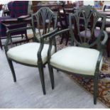 Two similar early 19thC green painted and stencilled elbow chairs with shield shaped backs,