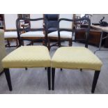 A pair of George III black painted and stencilled dining chairs with yellow fabric upholstered