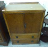 A 1920s oak cabinet with a pair of doors over two drawers,