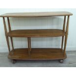 An Ercol beech and elm 'island' bookcase of oval outline, comprising three open tiers,