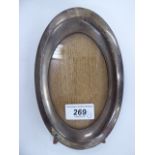 A silver photograph frame of oval form,