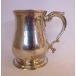 A George II silver mug of baluster form with an acanthus top, double C-scrolled handle,