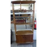 An Ercol beech and elm room divider of oval outline, comprising two fixed upper shelves,