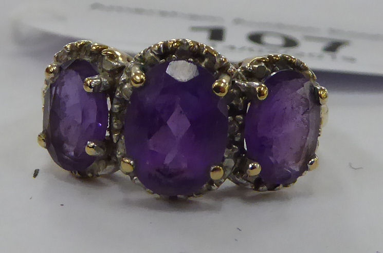 A 9ct gold three stone claw set amethyst and diamond ring 11