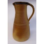 A toned brown and smudged green glazed studio pottery ewer of tapered form with a crimped spout and