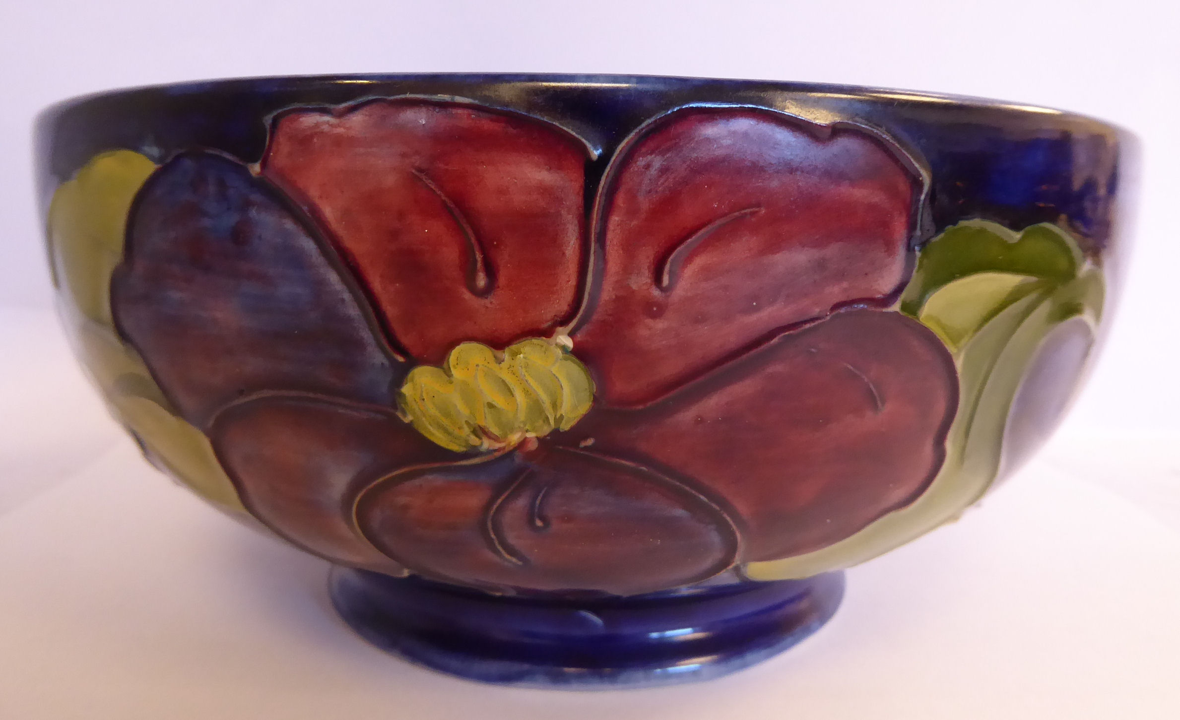 A Moorcroft pottery footed fruit bowl, decorated in tubeline in a version of the Anemone design,