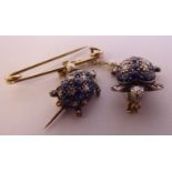 An 18ct gold coloured metal pin brooch with two sapphire and encrusted turtle pendants,