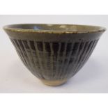 A green and brown glazed studio pottery bowl with flared sides and rib moulded ornament bears (an