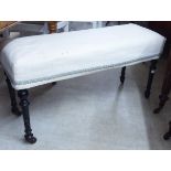 An Edwardian ebonised framed duet stool, the later fabric upholstered,