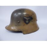 A German military painted camouflage helmet with a hide liner and chinstrap,