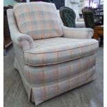 A modern armchair, upholstered in pastel coloured, patterned fabric,