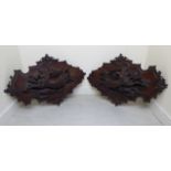 A pair of late 19thC North European, profusely carved mahogany wall plaques,