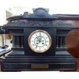 A late Victorian black slate cased mantel clock of architectural form;