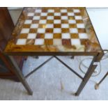 A modern brass framed table with a chessboard top, raised on rectangular legs,