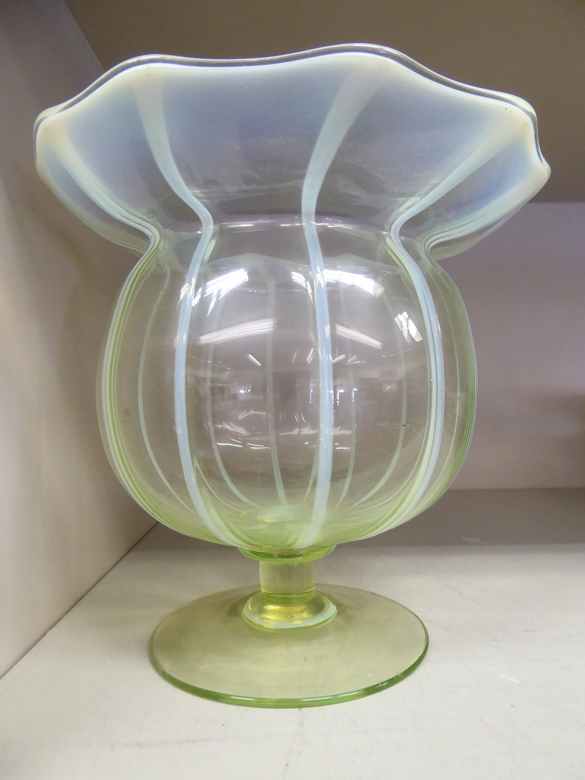 A vaseline glass vase of segmented, bulbous form with a wide, wavy rim,