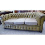 A modern three person buttoned green hide upholstered Chesterfield, raised on turned,