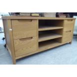 A modern light oak television stand with three open sections,
