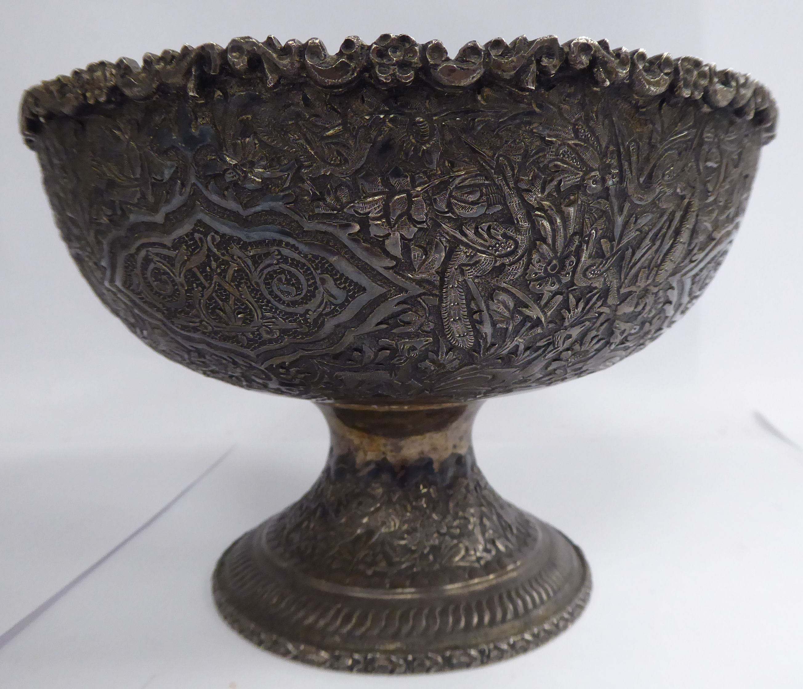 A Persian silver coloured metal bowl, elevated on a waisted pedestal foot,