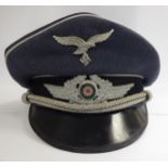 A German Luftwaffe visor cap with silvered braid and piping and a Nazi emblem (Please Note: this