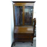 A 1920s mahogany bureau bookcase with a moulded cornice, over a pair of glazed doors,