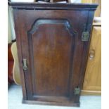 A George III oak hanging corner cabinet with a panelled door,