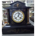 A late Victorian black slate cased mantel clock of architectural design;