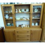 An Ercol elm sideboard, surmounted by a pair of display cabinets,