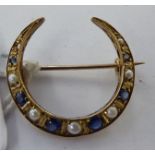 A yellow metal crescent brooch,