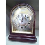 An early 20thC lacquered mahogany cased mantel clock with an arched top,